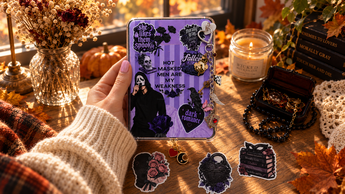 kindle insert that sits inside a clear kindle case with a keychain, stickers, a dust plug charm, and decorative fall elements around it in the image