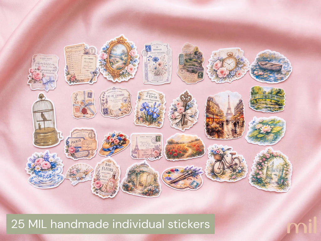 A flat lay of 25 vintage-style handmade individual stickers arranged on a pink satin fabric background. The stickers feature various illustrated designs including postcards, flowers, a birdcage, a bicycle, a clock, and scenic landscapes.