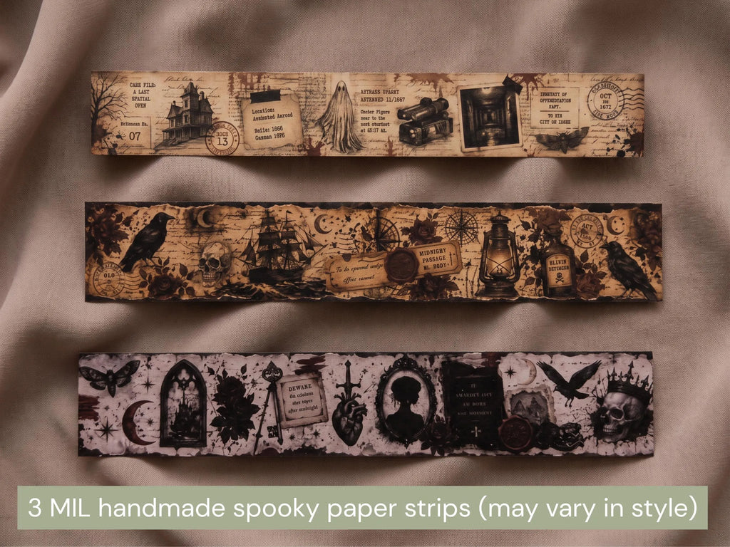Three horizontal strips of handmade spooky paper garland displayed on a draped beige fabric background. The top strip features a haunted house and vintage postmark theme, the middle strip shows a raven and lantern motif, and the bottom strip displays gothic arches, a skull, and a heart.