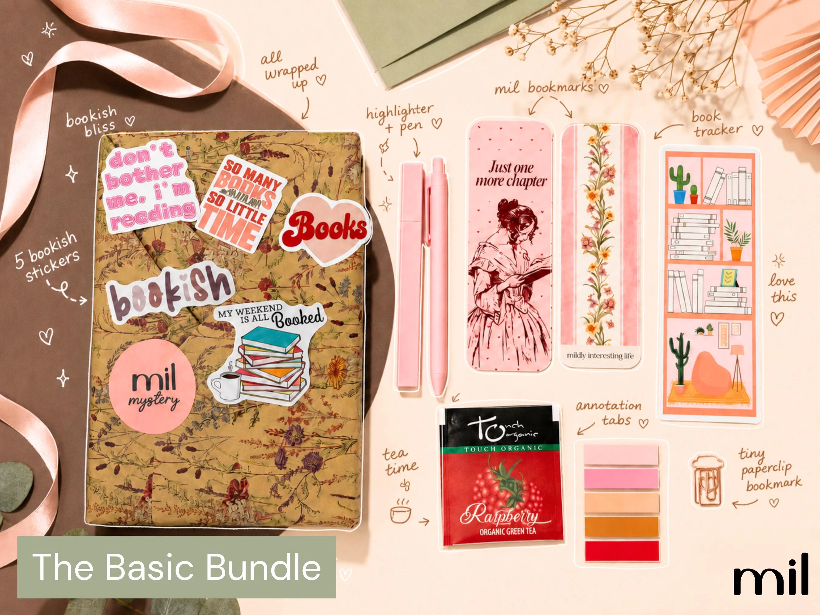 A styled flat-lay of a bookish-themed stationery bundle labeled 'The Basic Bundle,' blind date with a book featuring a kraft-paper book covered with stickers, a pink highlighter, a pink bookmark, floral bookmark strips, sticky notes, a tea bag, and other matching accessories on a beige background with ribbon and dried flowers.