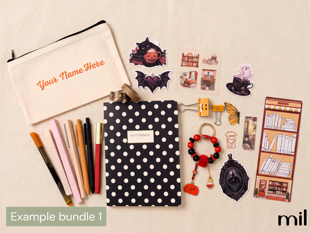 A flat-lay display of a customizable stationery and desk accessory bundle on a beige fabric background. The bundle includes a cream canvas pouch with orange text, a black and white polka dot notebook, paintbrushes, pens, stickers, a beaded keychain, and book-themed stickers.