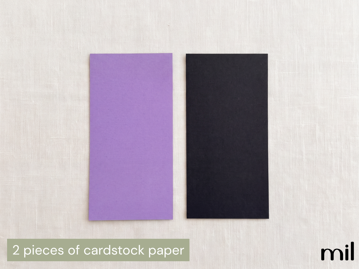Two rectangular pieces of cardstock paper, one in light purple and one in black, displayed side-by-side on a light beige textured background with a text overlay at the bottom left reading '2 pieces of cardstock paper'.