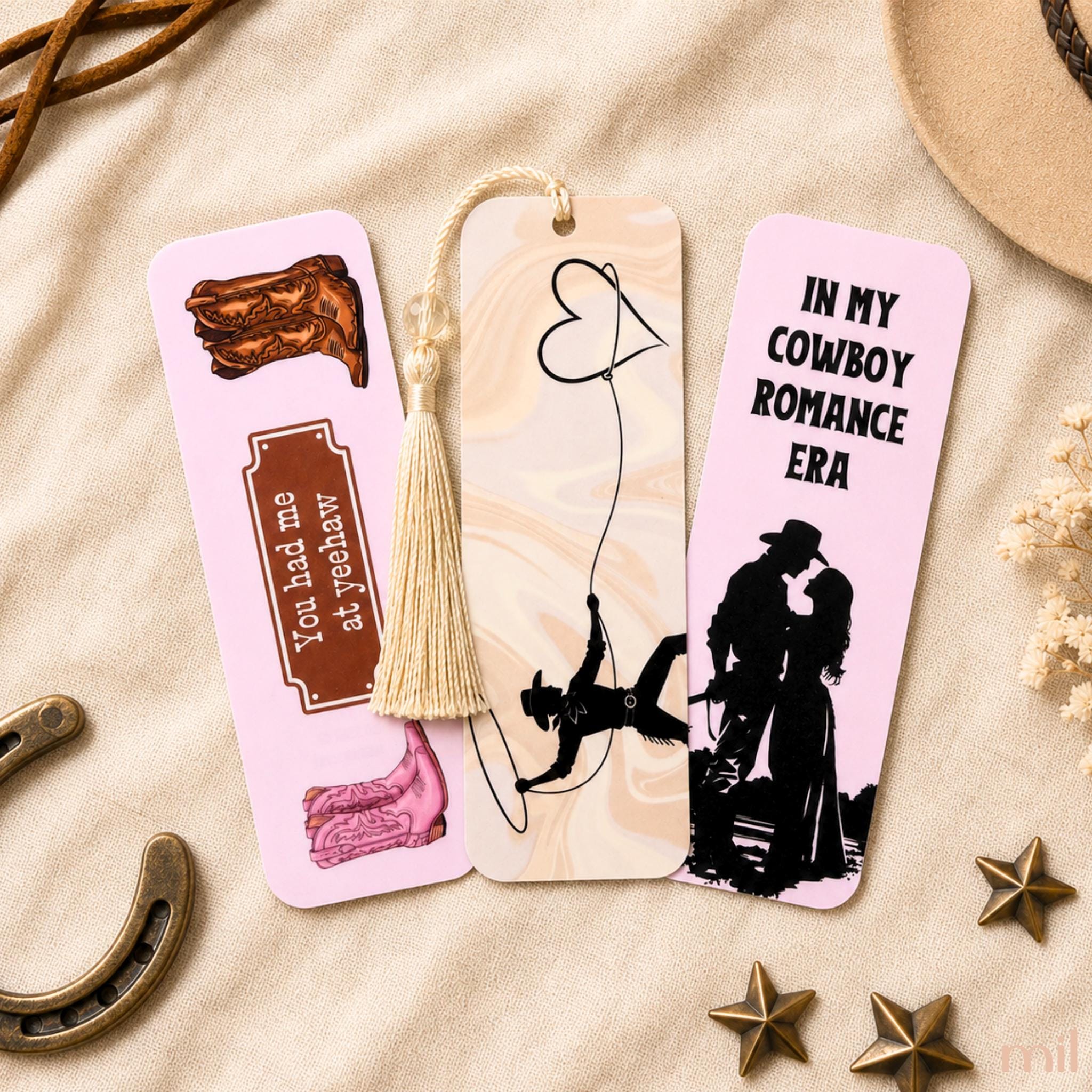 Three decorative bookmark cards arranged on a beige fabric surface with rustic props. 