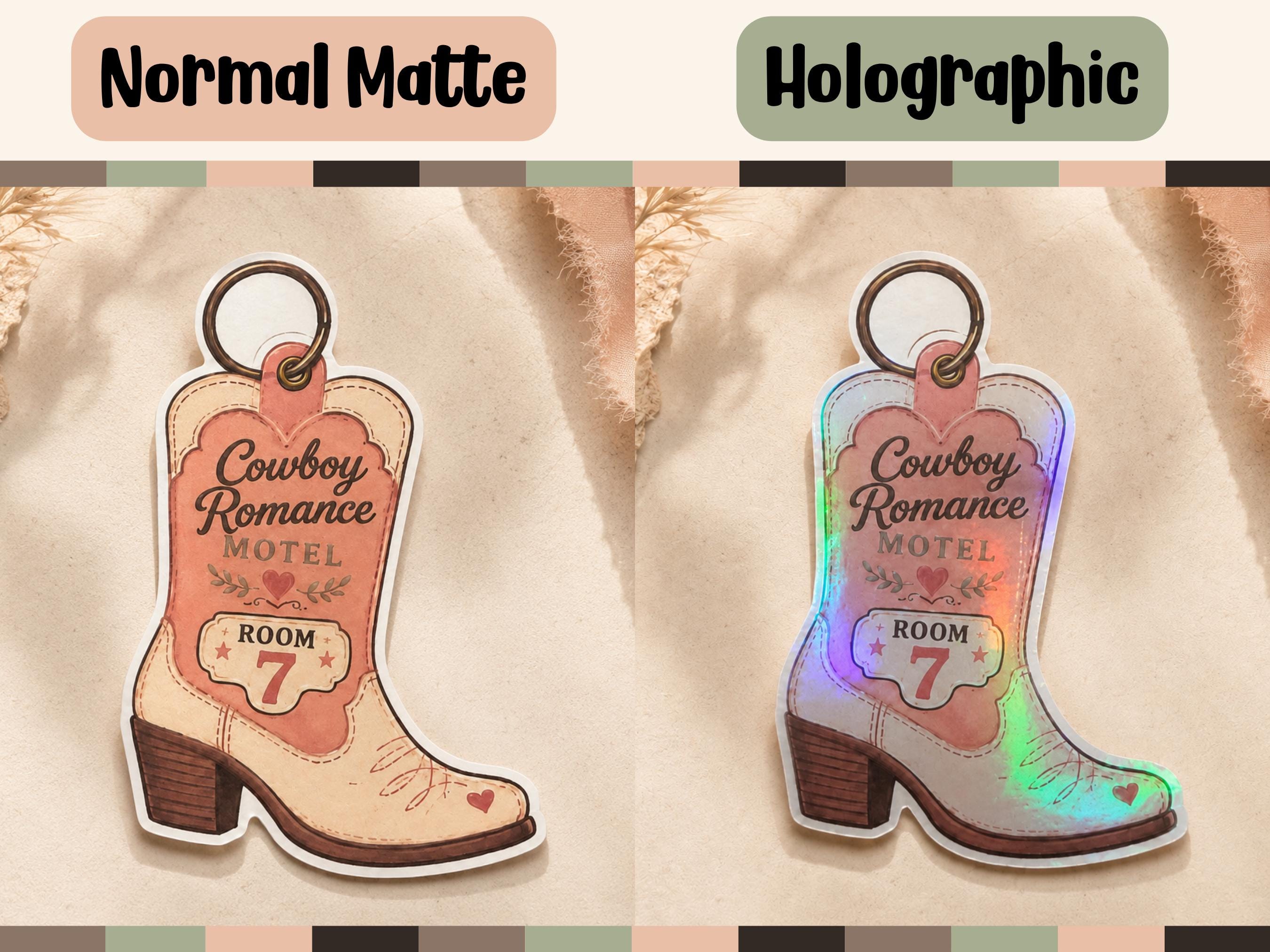 A side-by-side comparison of a cowboy boot-shaped keychain sticker in two finishes: 'Normal Matte' on the left and 'Holographic' on the right. The keychain features a pink and beige boot design with the text 'Cowboy Romance Motel ROOM 7'.