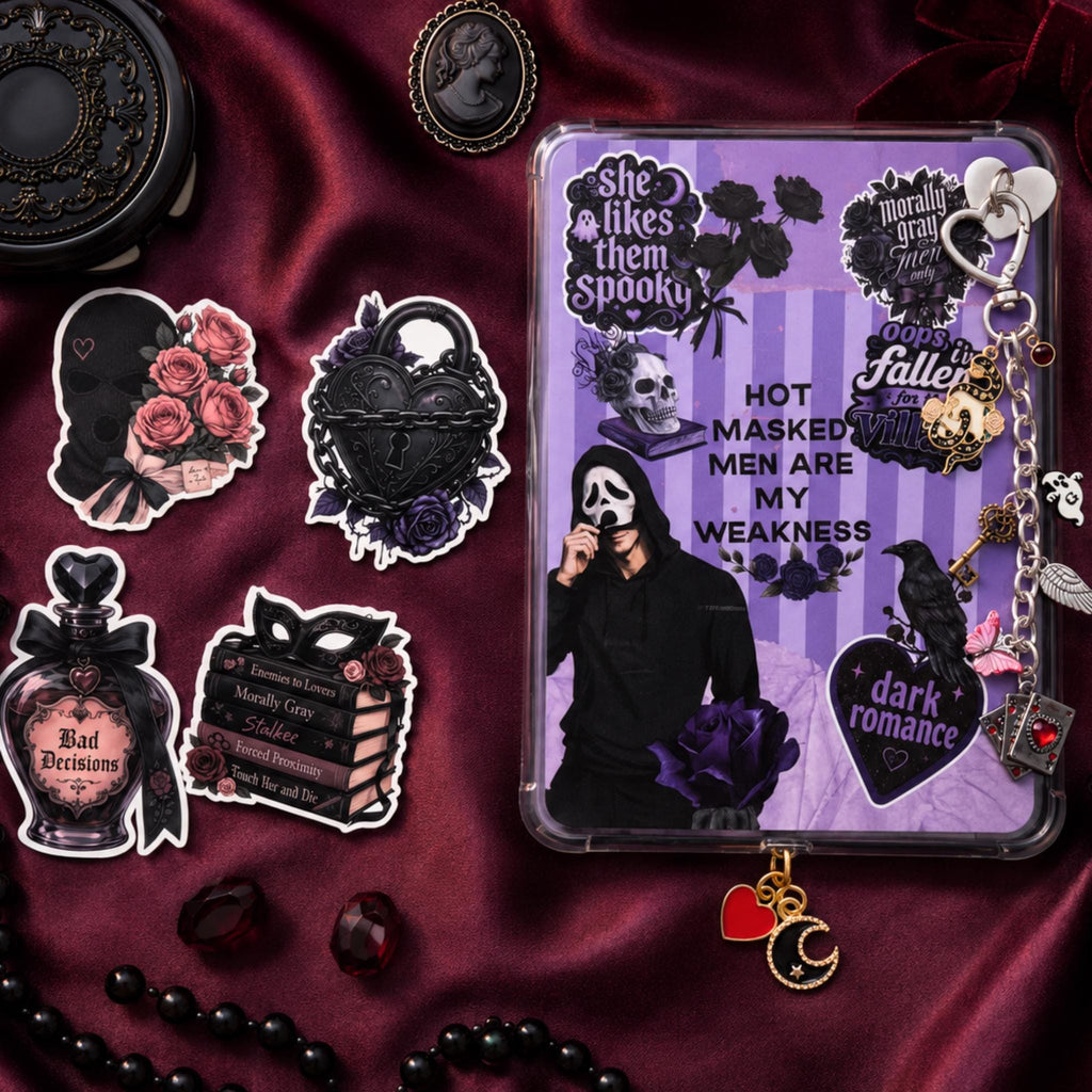 A dark romance-themed kindle insert with a purple striped background, skull, crows, roses, and text including 'HOT MASKED MEN ARE MY WEAKNESS' and 'dark romance.' The case is displayed on rich burgundy satin alongside matching decorative stickers and gothic accessories.
