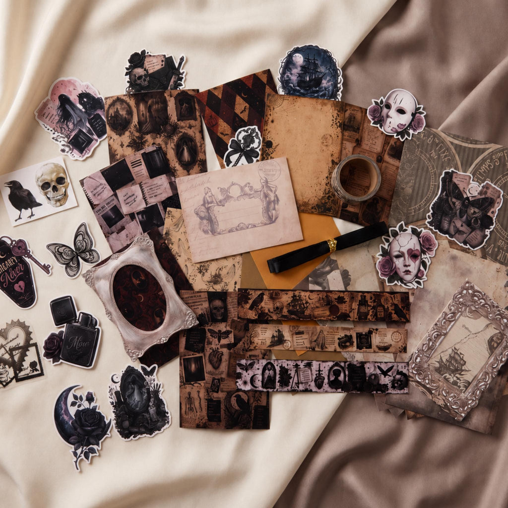A flat-lay arrangement of gothic-themed stickers and decorative paper strips on draped satin fabric. The collection features vintage illustrations of skulls, crows, roses, skeletons, and old photographs in muted sepia, black, and dusty pink tones.
