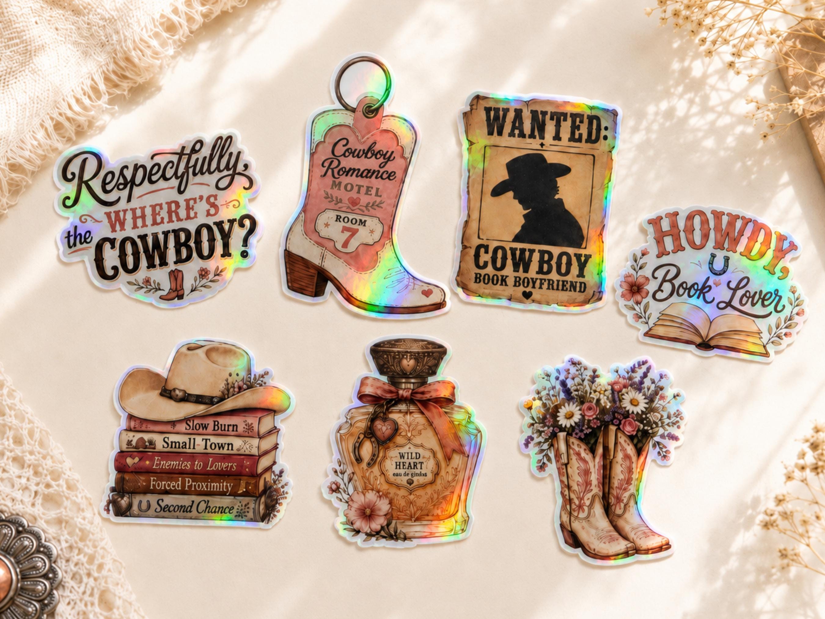 Six western-themed holographic stickers arranged on a textured cream fabric background. The stickers feature cowboy motifs including boots, a cowboy hat on books, a perfume bottle, a wanted poster, and text stickers reading 'Respectfully the COWBOY?', 'Cowboy Romance Hotel Room 7', 'WANTED: COWBOY BOOK BOYFRIEND', and 'HOWDY Book Lover'.