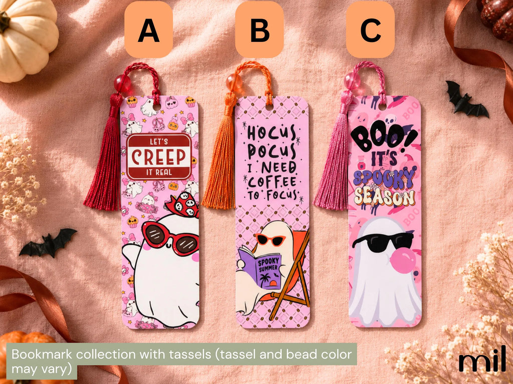 Three Halloween-themed bookmark sets with tassels are displayed on a textured pink fabric background. The bookmarks feature cute cartoon ghost illustrations with funny quotes: 'Let's CREEP IT REAL' on a red tassel, 'HOCUS POCUS I NEED COFFEE TO FOCUS' on an orange tassel, and 'BOO! IT'S SPOOKY SEASON' on a pink tassel.