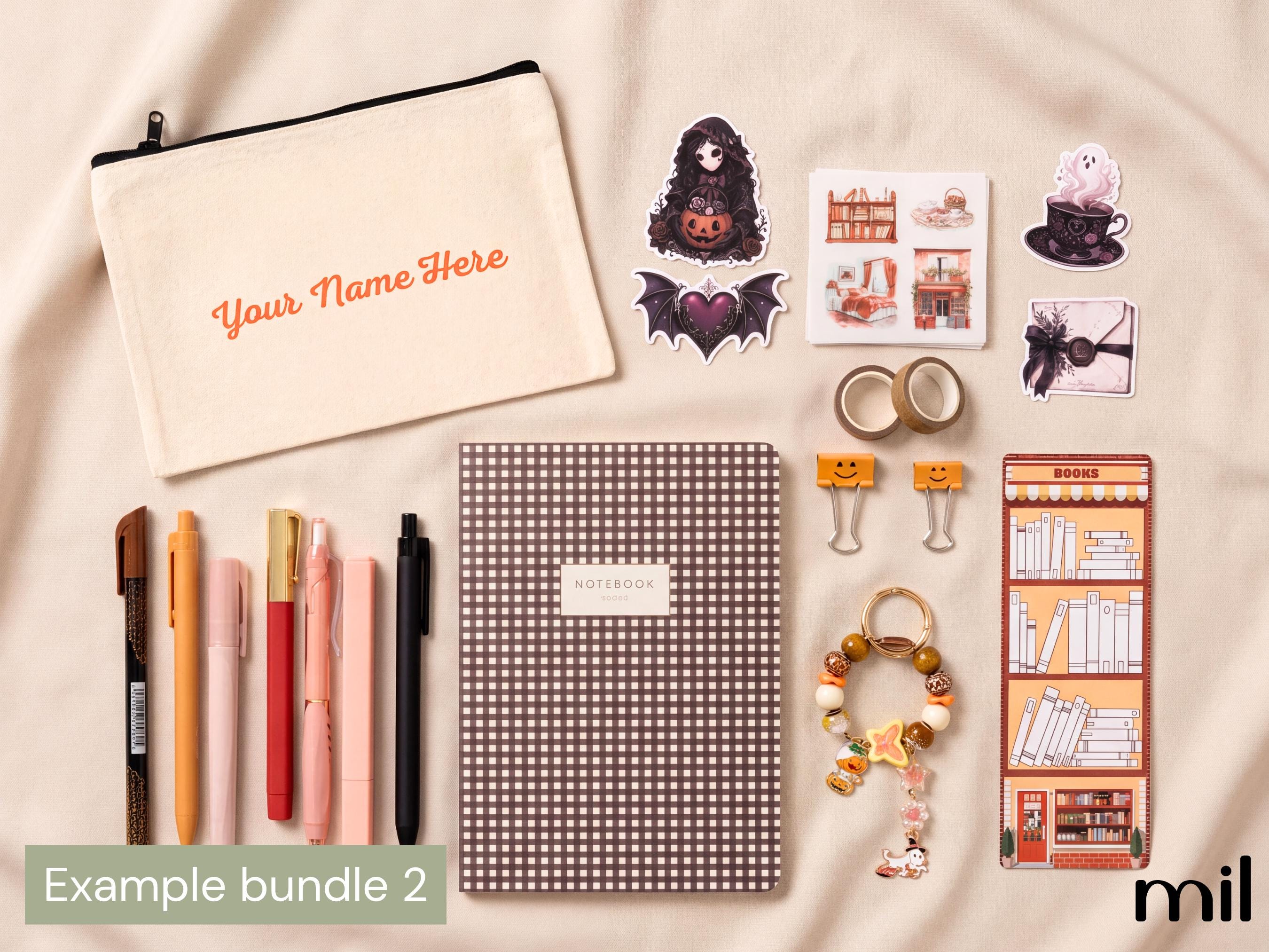 A flat-lay of a customizable stationery bundle on a beige fabric background. The set includes a cream canvas pouch with orange text, a brown-and-white checkered notebook, multiple pastel pens, stickers with Halloween and cozy illustrations, washi tape, binder clips, a beaded keychain, and a book-themed sticker sheet.