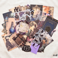 A flat-lay collage of vintage-style scrapbook papers, stickers, and decorative elements in muted sepia, black, cream, and purple tones, arranged on a light fabric background. A purple circular sticker or label is visible near the center, and the wordmark 'mil' appears in the bottom right corner.